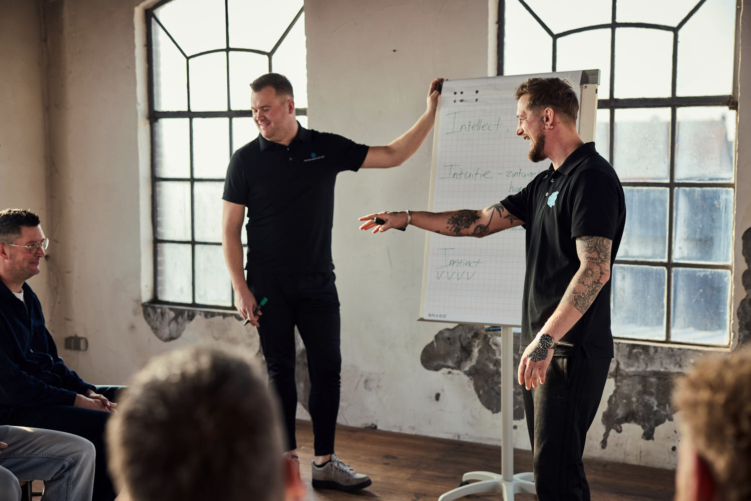 Twee trainers geven uitleg bij een flip-over tijdens een weerbaarheidstraining